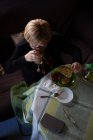 Von oben gealterte Frau trinkt Kaffee aus Glas beim Frühstück, während sie am Tisch sitzt — Stockfoto