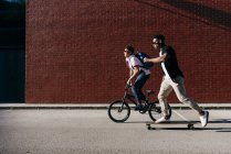 Young African American men riding bicycle and skateboard — Stock Photo