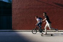 Giovani uomini afroamericani in bicicletta e skateboard — Foto stock