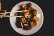 De cima mulher comendo servido apetecível barriga de porco quente com legumes como pepino e pimentão com pauzinhos — Fotografia de Stock