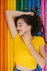 Hübsche junge Frau in lässigem Outfit fröhlich geschlossenen Augen, während sie auf Regenbogenbank-Hintergrund liegt — Stockfoto