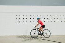 Feminino no capacete e sportswear andar de bicicleta na rua da cidade no dia ensolarado — Fotografia de Stock