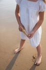 Невпізнана дівчина тримає морську зірку на березі моря в літній день — стокове фото