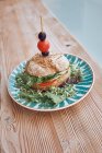 Смачний вегетаріанський бутерброд з помідорами, цибулею, салатом, оливками та вишневим помідором на яскравій тарілці на дерев'яному столі в ресторані — стокове фото