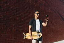 Young black man with long board speaking on phone — Stock Photo