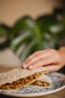 Hand halten serviert appetitliche chinesische Burger mit Schweinefleisch, Sternanis, Zimt und heiß gedämpftem Brötchen auf Teller im asiatischen Café — Stockfoto