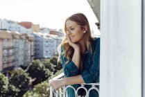 Jeune femme regardant loin sur le balcon — Photo de stock