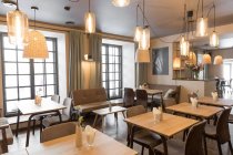 Elegante lámpara que brilla sobre pequeñas mesas y cómodas sillas en el acogedor restaurante - foto de stock