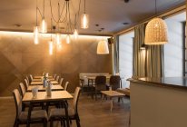 Stilvolle Lampe strahlt über kleine Tische und bequeme Stühle im gemütlichen Restaurant — Stockfoto