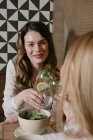 Deux jolies dames souriantes et cliquetis verres de cocktails alcoolisés tout en déjeunant dans un restaurant confortable ensemble — Photo de stock