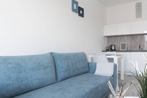 Moderna sala de estar mobilada com paredes brancas e teto e sofá em azul — Fotografia de Stock