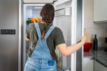 Unrecognizable female taking fresh pear from shelf of refrigerator at home — Stock Photo