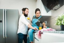 Paar trinkt Orangensaft und isst gesundes Essen, während es Zeit in der Küche zu Hause zusammen verbringt — Stockfoto
