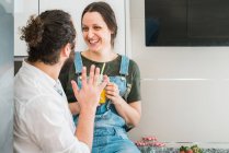 Пара п'є апельсиновий сік і їсть здорову їжу, проводячи час на кухні вдома разом — стокове фото
