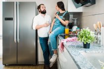 Casal beber suco de laranja e comer alimentos saudáveis enquanto passa o tempo na cozinha em casa juntos — Fotografia de Stock
