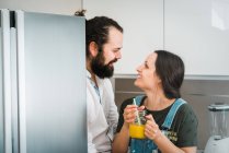 Couple boire du jus d'orange et manger des aliments sains tout en passant du temps sur la cuisine à la maison ensemble — Photo de stock