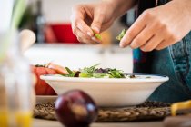 Imagem cortada de mulher em casaco multicolorido preparando legumes enquanto cozinha salada saudável na cozinha — Fotografia de Stock