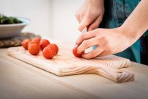 Imagem cortada de mulher cortando tomates enquanto cozinha salada saudável na cozinha — Fotografia de Stock