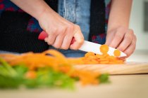 Abgeschnittenes Bild einer Frau, die Karotten schneidet, während sie in der Küche gesunden Salat kocht — Stockfoto