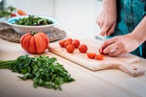 Immagine ritagliata di donna che taglia pomodori durante la cottura di insalata sana in cucina — Foto stock