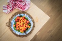 Разноцветный салат с помидорами черри в миске на кухонном столе — стоковое фото