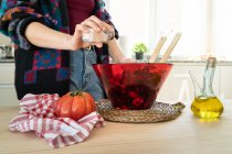 Image recadrée de la femme en veste multicolore mettre du sel sur la salade saine dans un bol — Photo de stock