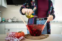 Обрезанный образ женщины в разноцветной куртке положить оливковое масло здоровый салат в миску — стоковое фото
