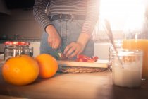 Imagen recortada de la mujer en traje casual cortar fresas frescas en una cocina - foto de stock