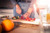 Imagem cortada de mulher em roupa casual cortando morangos frescos em uma cozinha — Fotografia de Stock