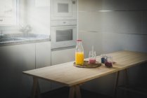 Recipientes com bagas frescas e bebidas saudáveis colocadas na mesa na cozinha moderna — Fotografia de Stock