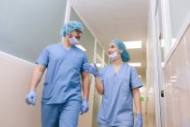 Товариші хірурги чоловік і жінка спілкуються під час прогулянки до операційного театру — стокове фото
