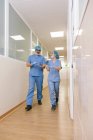 Коллеги хирурги мужчина и женщина беседуют во время ходьбы к операционной — стоковое фото