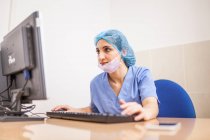 Cirujano femenino usando su computadora en su consultorio antes de la cirugía - foto de stock