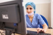 Cirujano femenino usando su computadora en su consultorio antes de la cirugía - foto de stock