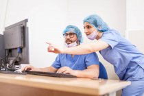 Team of surgeons, man and woman using the computer before the surgery and committing the details — Stock Photo