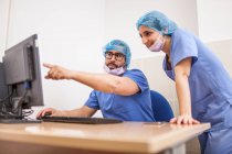 Équipe de chirurgiens, homme et femme utilisant l'ordinateur avant l'opération et commettant les détails — Photo de stock
