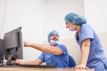 Команда хірургів, чоловік і жінка використовують комп'ютер перед операцією і роблять деталі — стокове фото