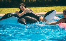 Mujeres con juguetes inflables en la piscina - foto de stock
