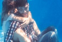 Жінка обіймає чоловіка в одязі під водою і посміхається . — стокове фото