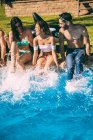 Друзі сидять на березі басейну і плескають ногами — стокове фото