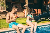 Couple s'amuser assis à la piscine — Photo de stock