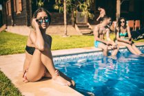 Girl in sunglasses sitting at swimming pool — Stock Photo