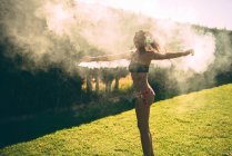 Pretty girl wearing swimsuit posing with smoke torch on pool party in yard. — Stock Photo