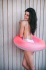 Chica con un anillo de natación posando por cerca de madera blanca - foto de stock