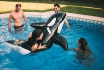 Friends swimming on inflatable toy in pool — Stock Photo