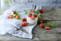 Creamy sweet dessert with fresh juicy strawberries served in glass on rustic wooden table — Stock Photo