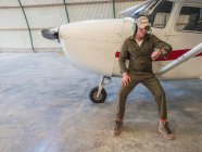 Pilota in attesa vicino aereo retrò in hangar — Foto stock