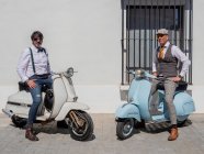 Positive Hipster mittleren Alters in eleganter Kleidung mit Retro-Motorrädern blicken bei sonnigem Wetter in die Kamera — Stockfoto
