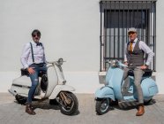 Positivi hipster di mezza età in abiti eleganti con moto retrò che guardano la fotocamera nella giornata di sole — Foto stock