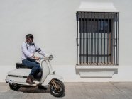 Позитивный хипстер средних лет в элегантной одежде с ретро мотоциклом, смотрящим в солнечный день — стоковое фото